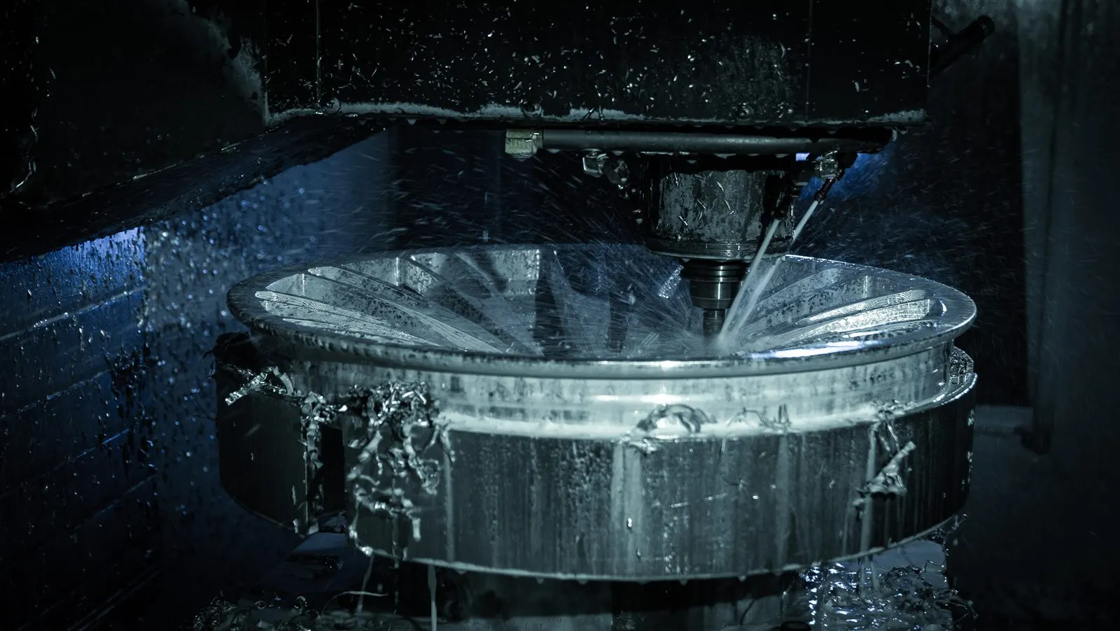 Five-axis CNC mill cutting a wheel face under coolant
