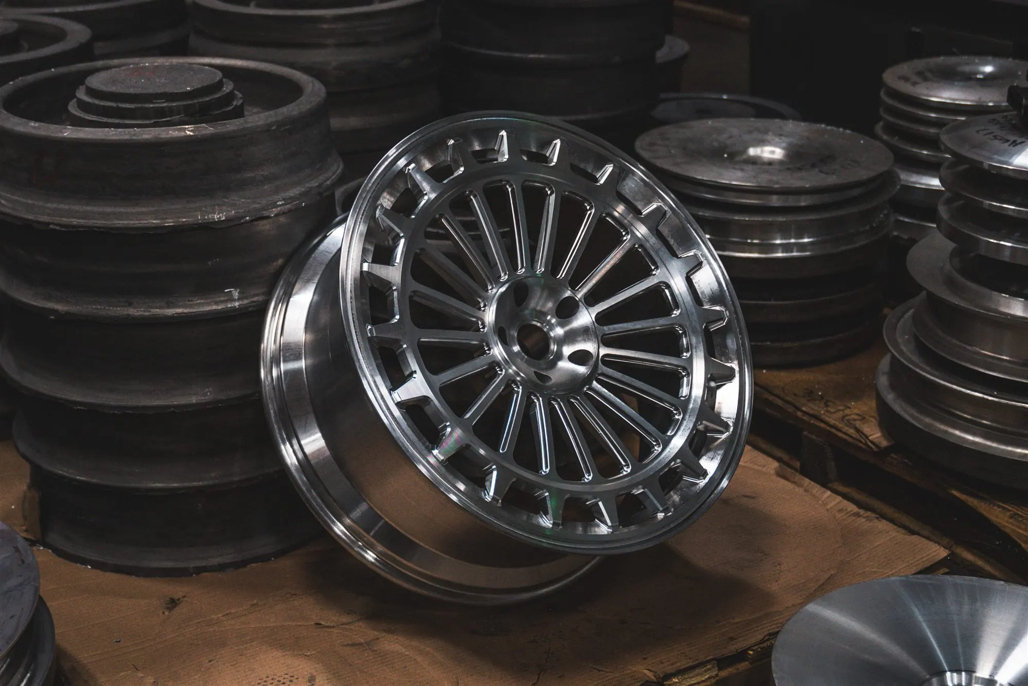 Freshly machined wheel among raw forging blanks