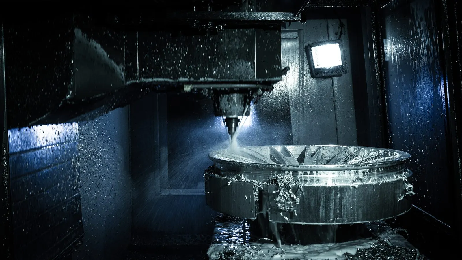 A wheel being machined under coolant inside the CNC enclosure